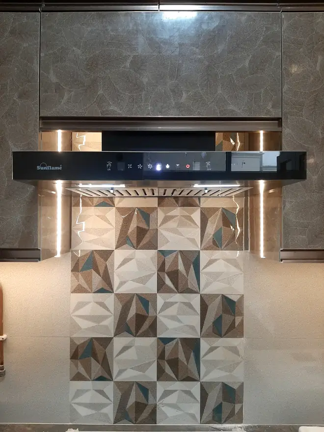 Chimney fitted over a hob against a marble splashback and patterned tile