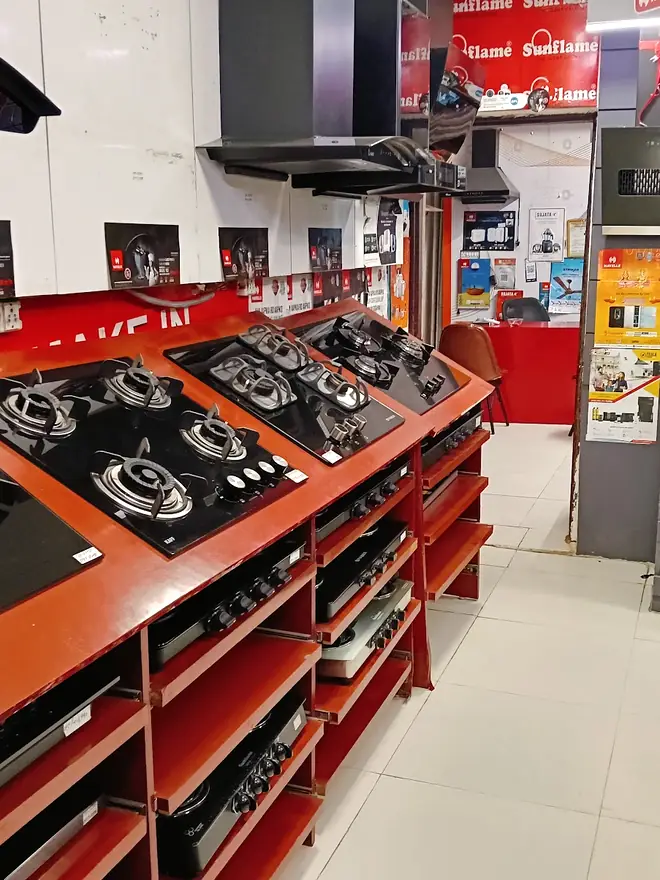 Red display racks holding glass-top gas hobs in the middle of the shop