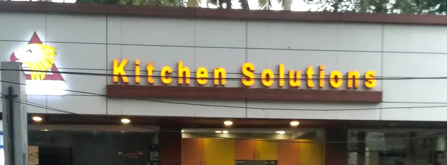 The lit Kitchen Solutions sign on the shopfront at dusk